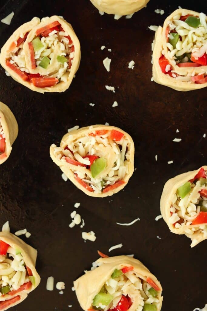 Overhead shot of unbaked pizza pinwheels on baking sheet