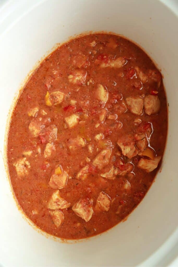 Overhead shot of slow cooker filled with cooked chicken, vegetables, and broth.