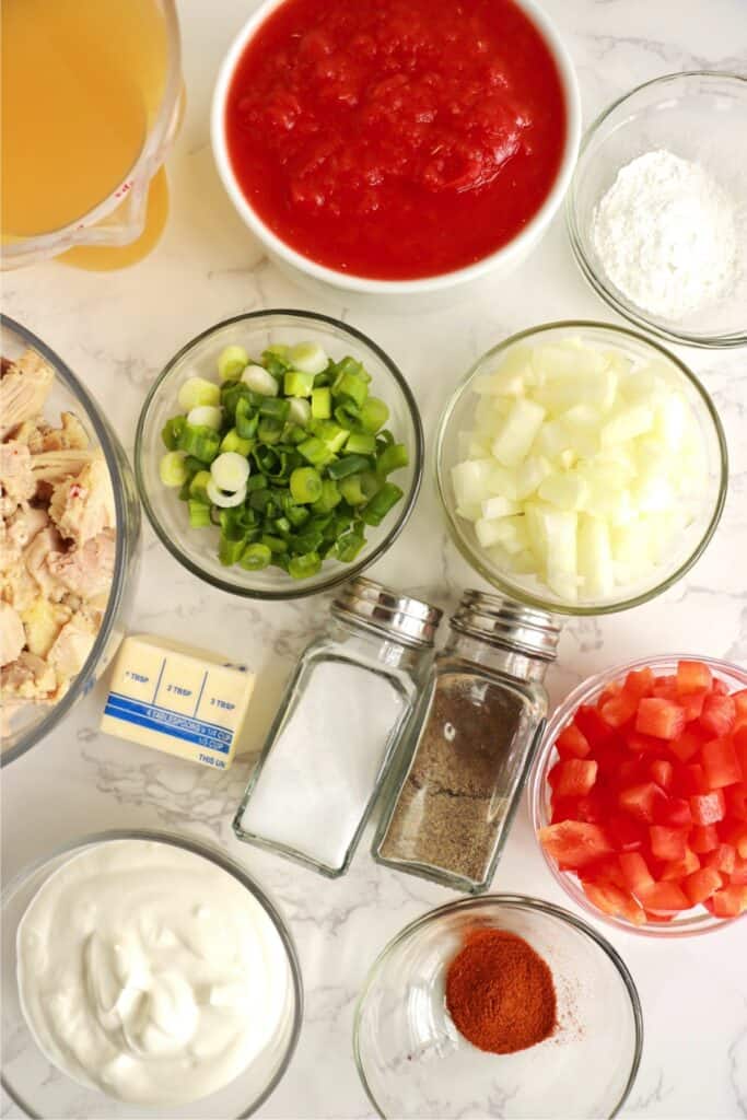 Overhead shot of chicken paprikash soup ingredients in individual bowls on table