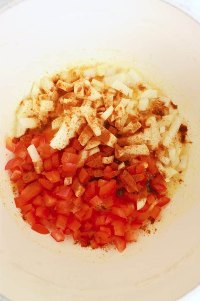 Close up overhead shot of onions and bell peppers in skillet