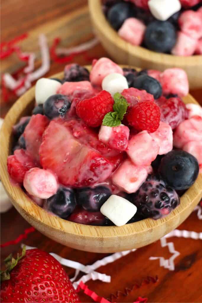 Bowlful of healthy fruit salad with another bowl of fruit salad in background.