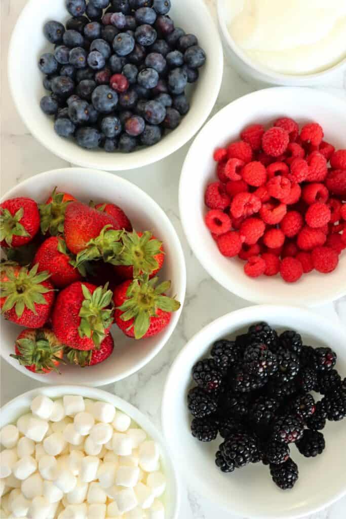 Overhead shot of healthy fruit salad recipe ingredients in individual bowls on table