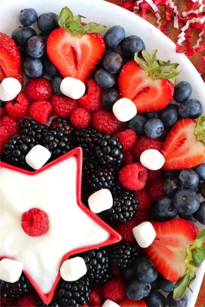 Closeup overhead shot of mixed berry fruit tray with star-shaped bowl of yogurt in center. 