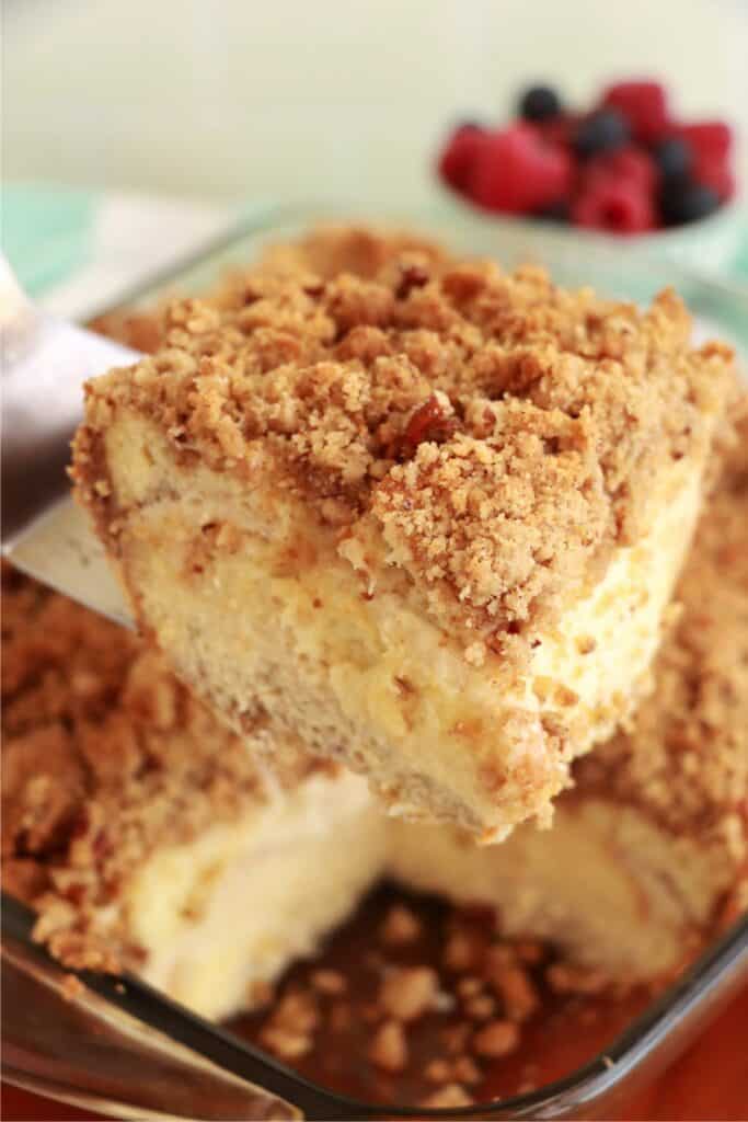 Closeup shot of spatula with slice of cream cheese stuffed French toast over baking dish with more French toast