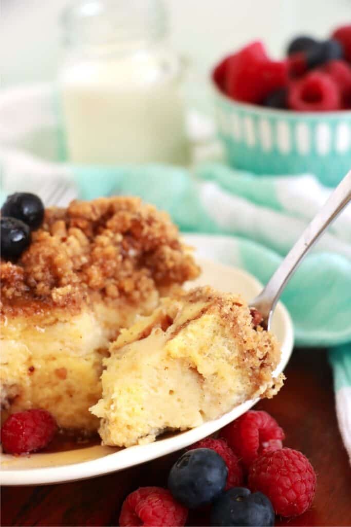 Closeup shot of forkful of cream cheese stuffed French toast next to slice of French toast on plate