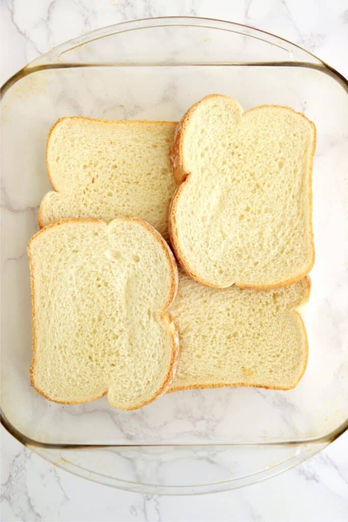 Overhead shot of bread slices in bottom of baking dish