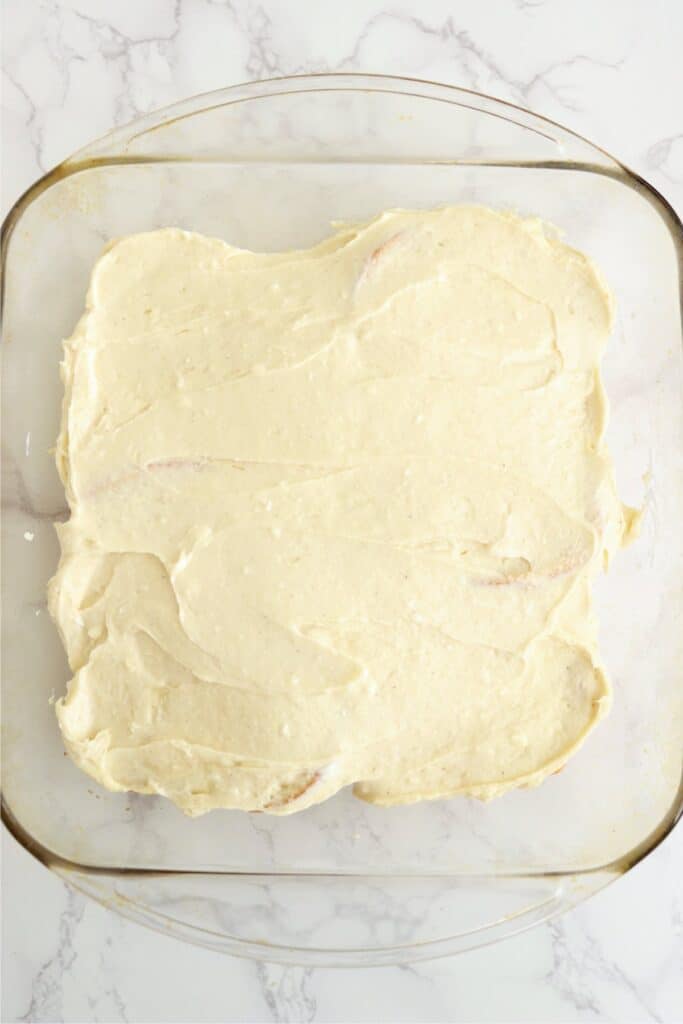 Overhead shot of bread slices in baking dish covered with cream cheese mixture. 