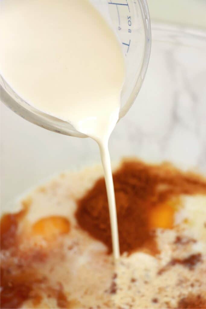 Closeup shot of heavy whipping cream being poured into bowlful of French toast egg custard ingredients