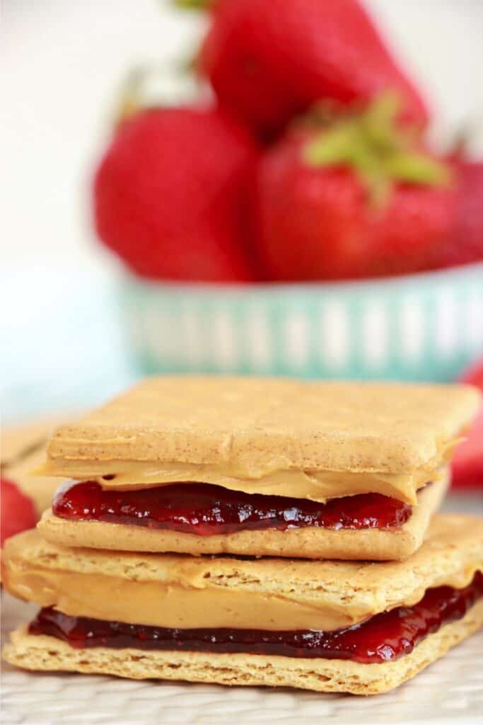Closeup shot of two peanut butter and jelly graham cracker sandwiches stacked atop one another. 