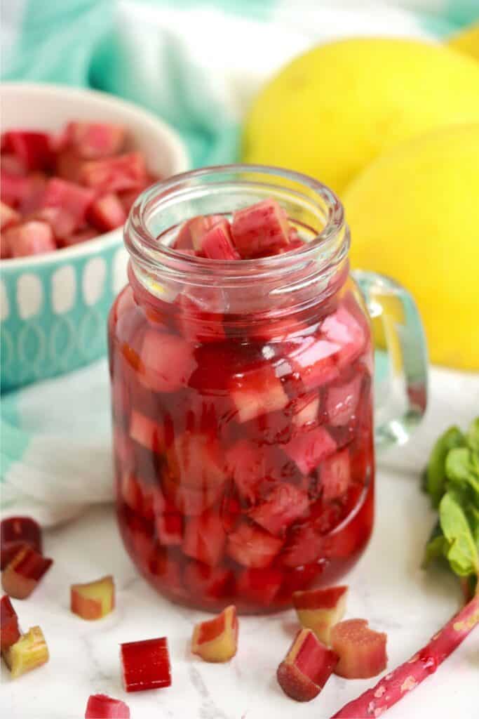 Jarful of pickled rhubarb with bowl of rhubarb in background