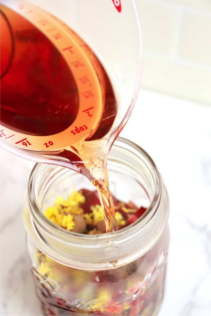 Brine being poured into jarful of rhubarb and lemon zest