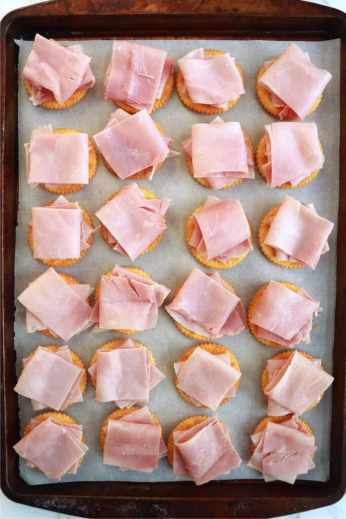 Overhead shot of ham slices on Ritz crackers on baking sheet.
