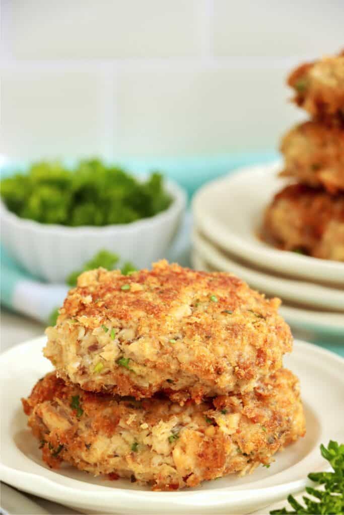 Two salmon patties stacked atop one another on plate. 