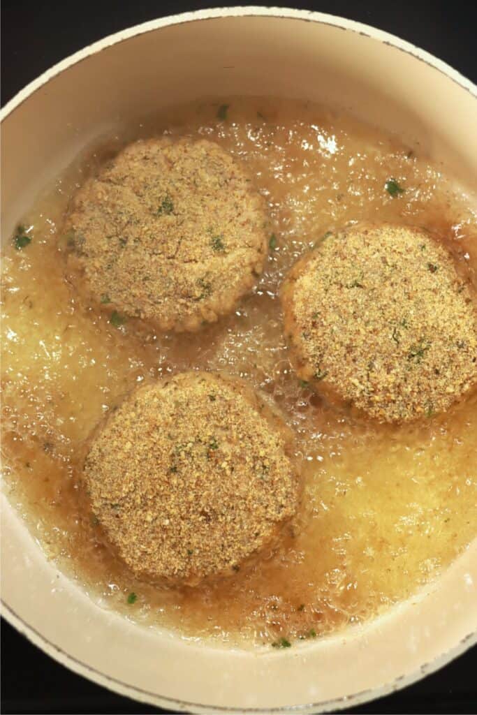 Overhead shot of breaded salmon patties frying in oil 