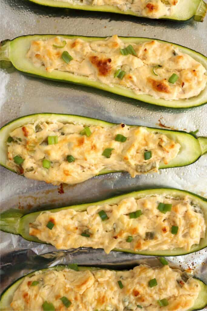 Overhead shot of baked Buffalo chicken zucchin boats on baking sheet lined with foil. 