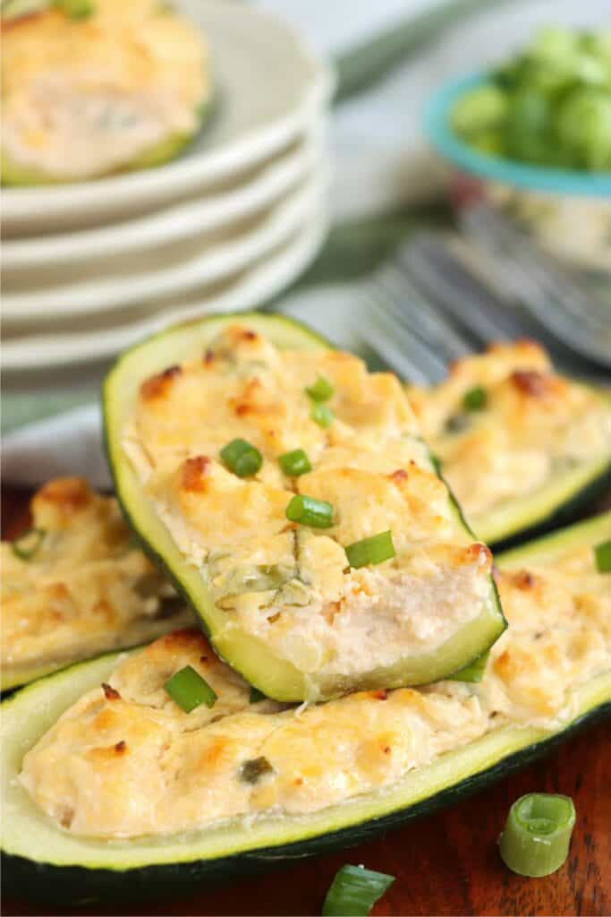 Closeup shot of Buffalo chicken zucchini boats stacked atop one another with top zucchini boat cut in half. 