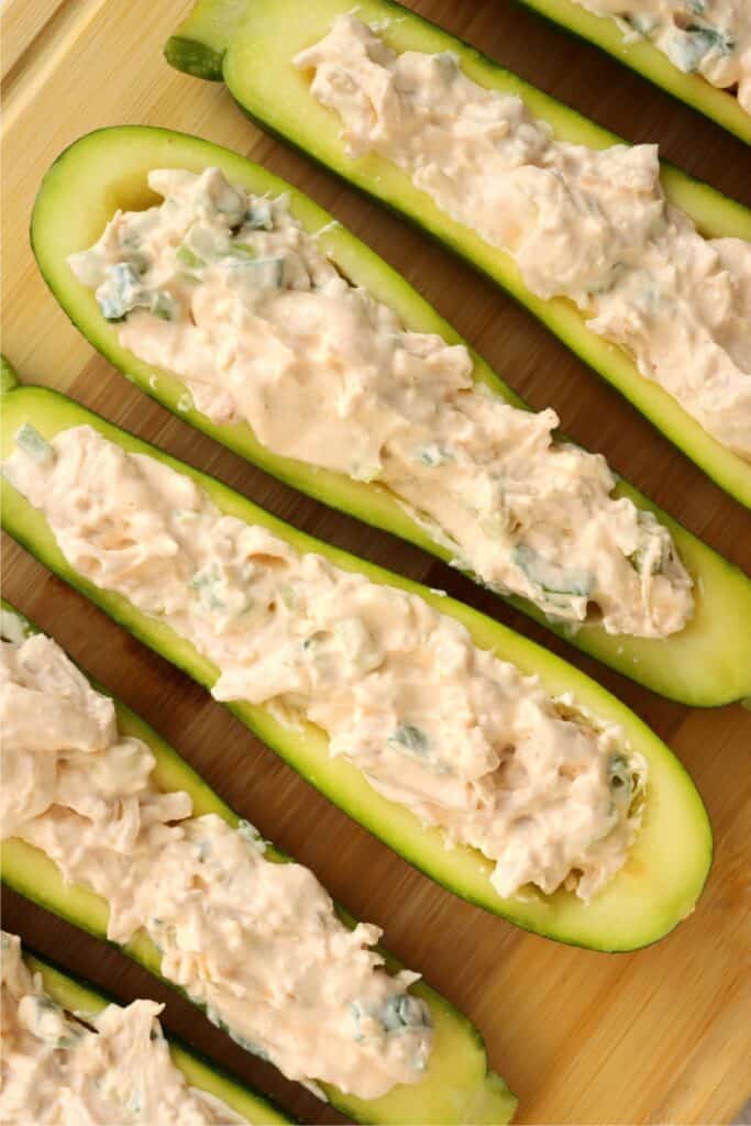 Overhead shot of unbaked Buffalo chicken zucchini boats on cutting board