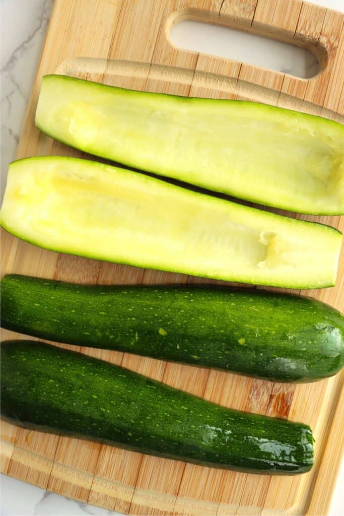 Overhead shot of zucchini halves with seeds removed on cutting board.