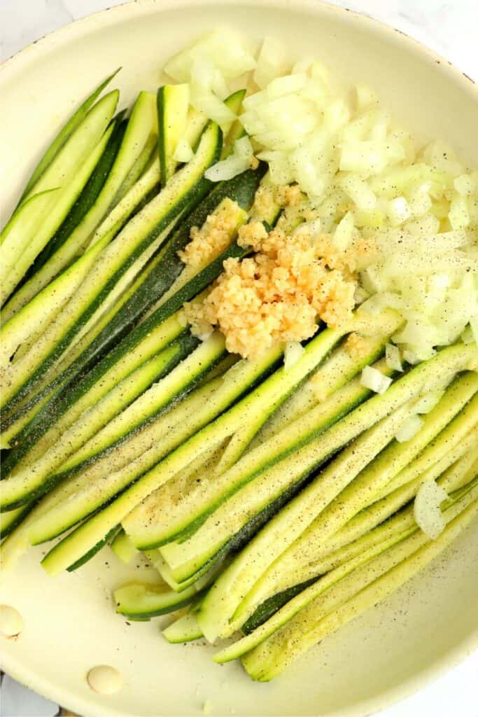 Overhead shot of zucchini, onions, and garlic in skillet. 