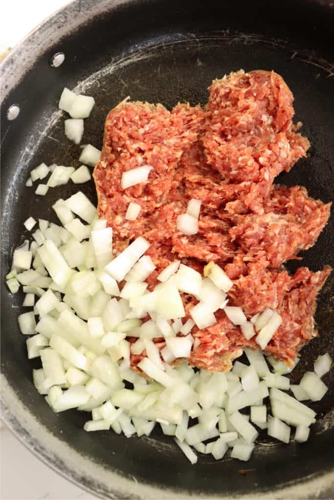Overhead shot of beef and diced onions in skillet