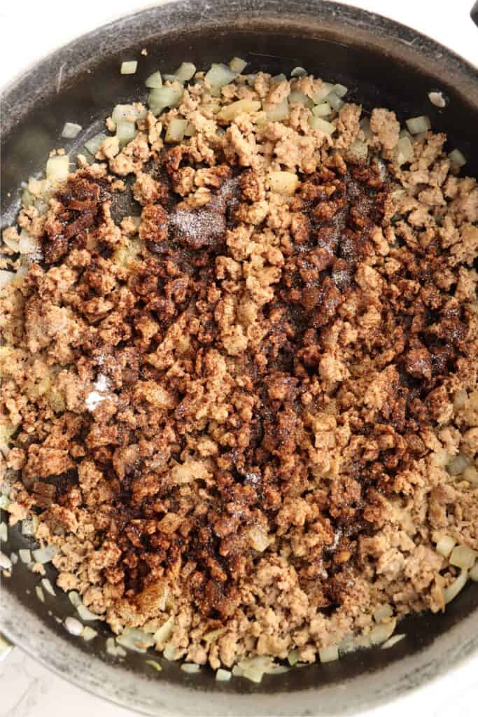 Overhead shot of beef and onions in skillet sprinkled with southwestern spices.