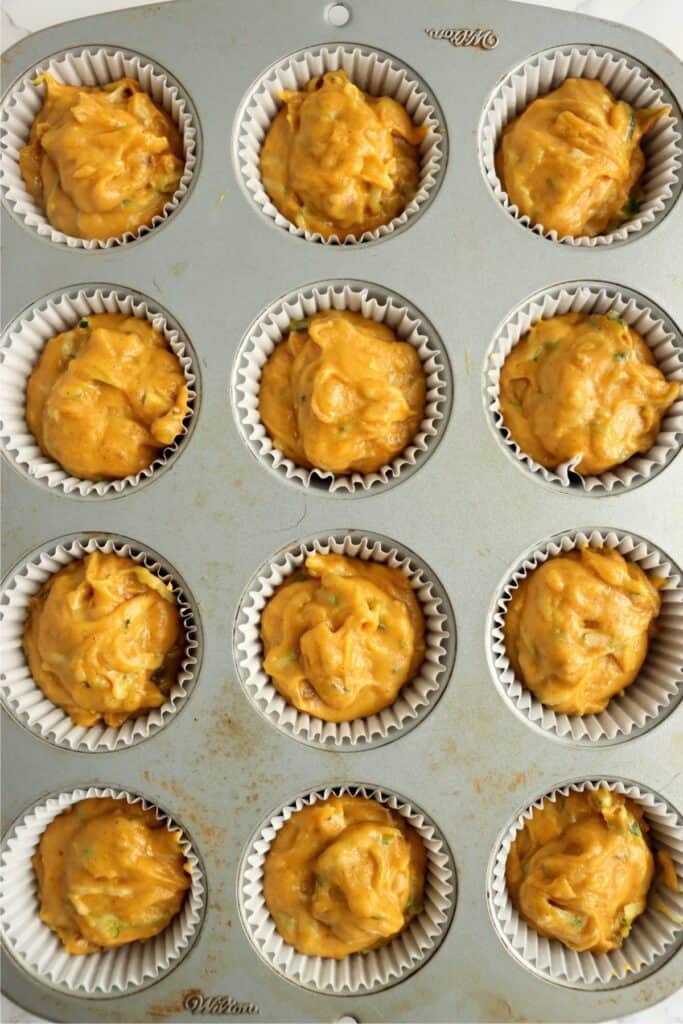 Overhead shot of pumpkin zucchini muffin batter in muffin tin.