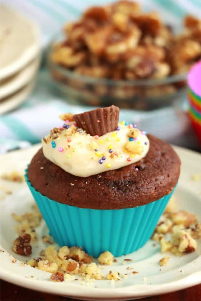 Closeup shot of cream cheese stuffed chocolate cupcake topped with cream cheese frosting and a mini Reese's cup