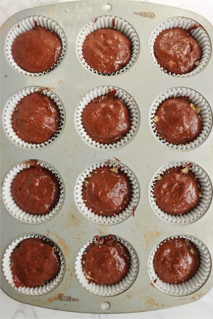 Overhead shot of cupcake liners half filled with chocolate cake batter. 