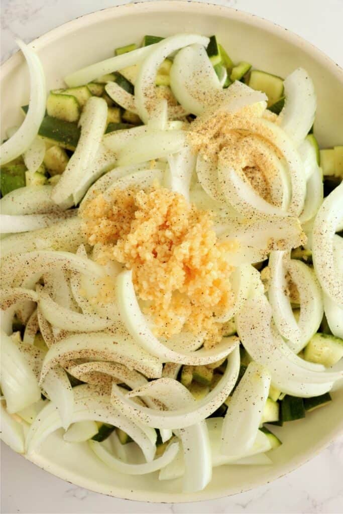 Closeup overhead shot of zucchini, onions, and spices in skillet. 