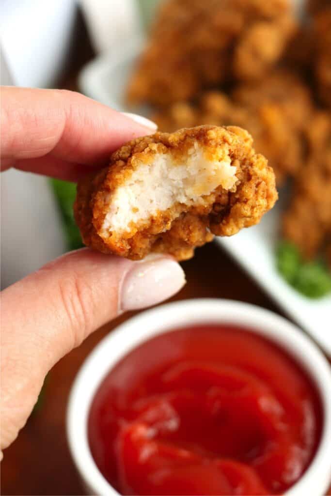 Closeup shot of hand holding a Tyson air fryer chicken strip with bite taken out.