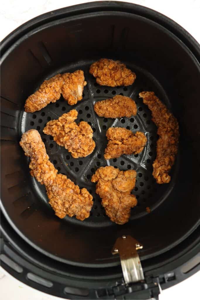 Overhead shot of frozen Tyson chicken strips in air fryer basket. 