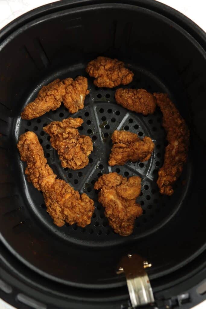 Overhead shot of cooked Tyson chicken strips in air fryer basket.