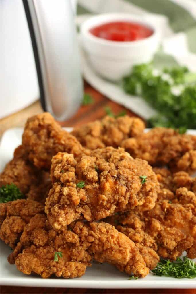 Closeup shot of Tyson air fryer chicken strips stacked atop one another on plate.