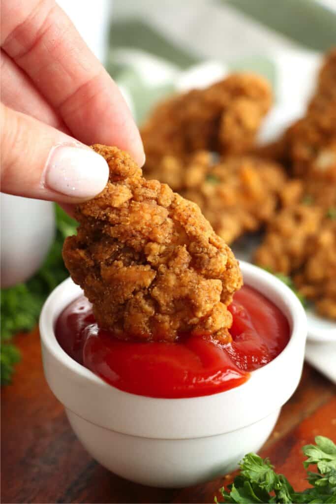 Closeup shot of Tyson air fryer chicken strip being dipped into ketchup. 