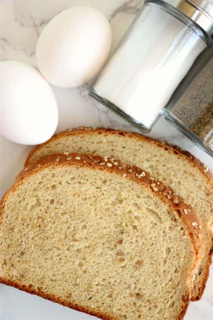 Overhead shot of two slices of bread next to two eggs and salt and pepper shakers. 