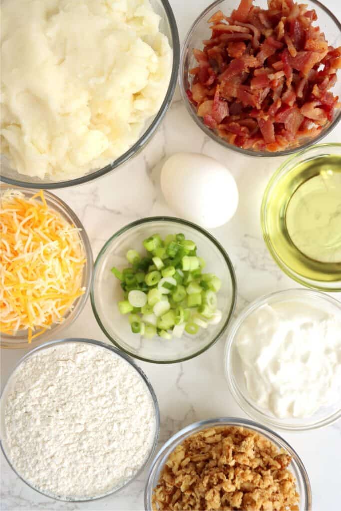 Overhead shot of individual mashed potato patties recipe ingredients in bowls on table. 