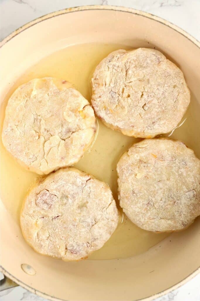 Flour cated mashed potato patties in skillet with oil. 