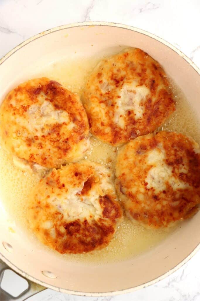 Overhead shot of golden brown mashed potato patties frying in oil