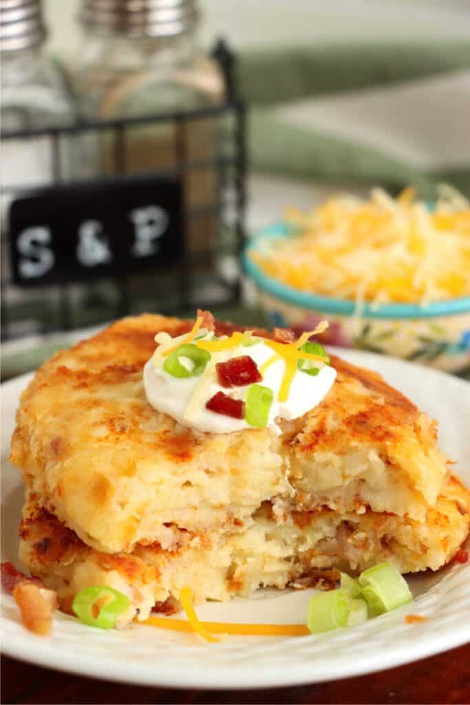 Closeup shot of two bacon and cheese potato patties stacked atop one another on plate with piece cut out of both patties.