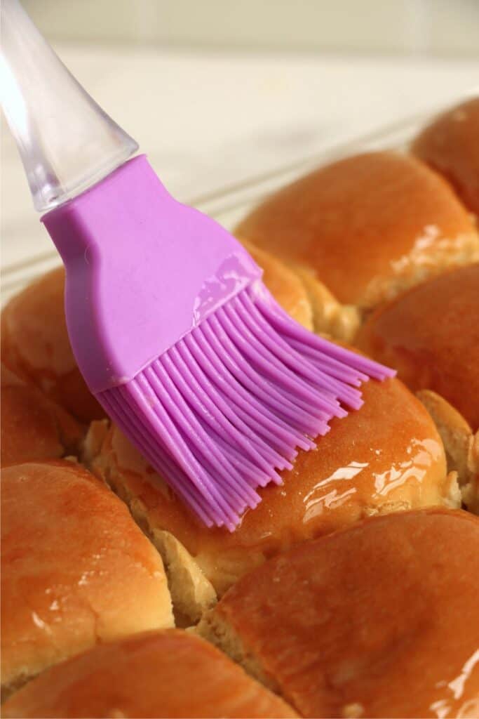 Closeup shot of butter being brushed onto corned beef sliders. 