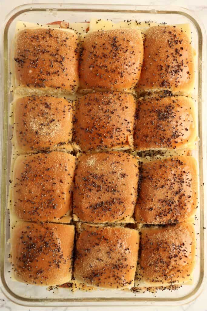 Overhead shot of unbaked corned beef sliders topped with garlic powder and poppy seeds. 