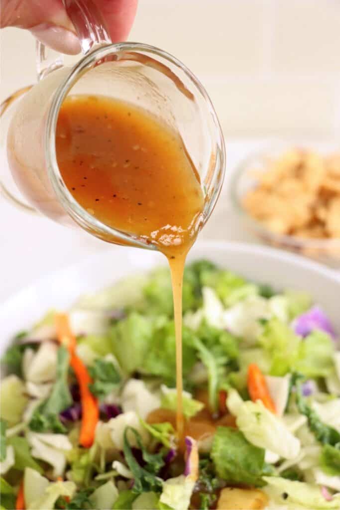 Dressing being poured over Asian salad. 