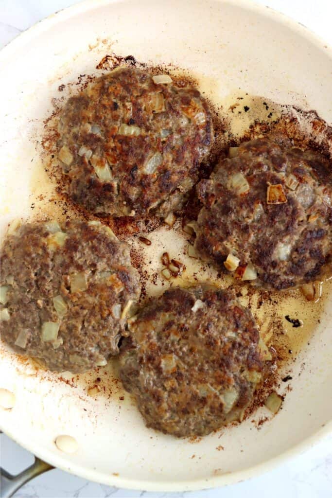 Overhead shot of cooked classic American burgers in skillet. 