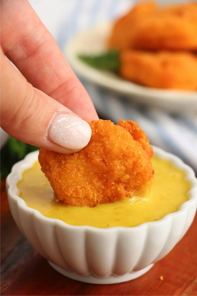 Closeup shot of Tyson air fryer chicken nugget being dipped in honey mustard. 