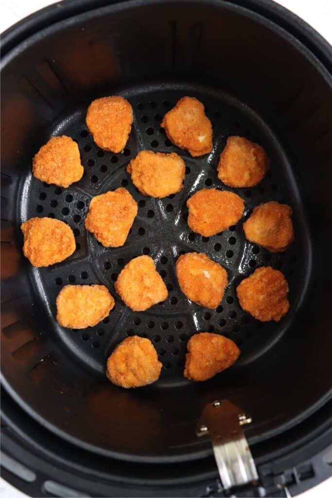 Overhead shot of fozen Tyson chicken nuggets in air fryer basket. 