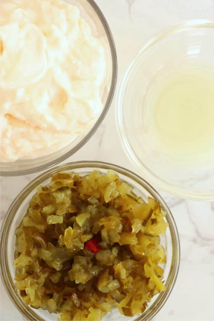 Overhead shot of individual tartar sauce ingredients in bowls. 