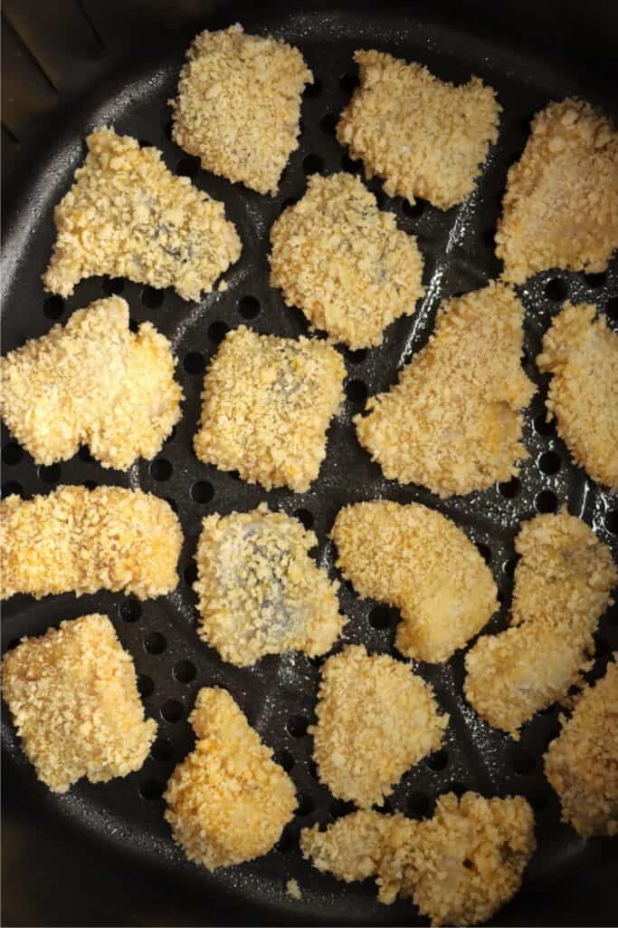 Overhead shot of uncooked breaded catfish nuggets in air fryer basket.