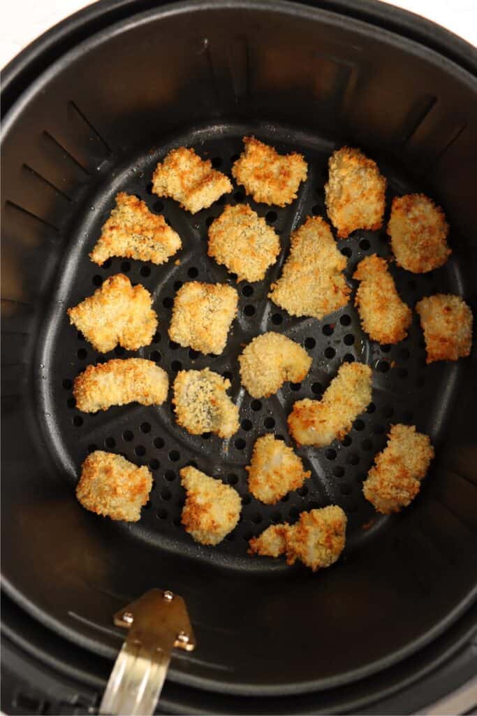 Overhead shot of golden brown air fryer catfish nuggets in air fryer basket. 