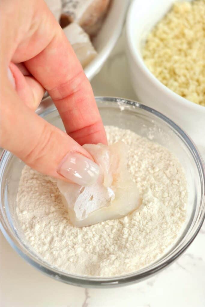 Closeup shot of catfish nugget being dipped in flour. 