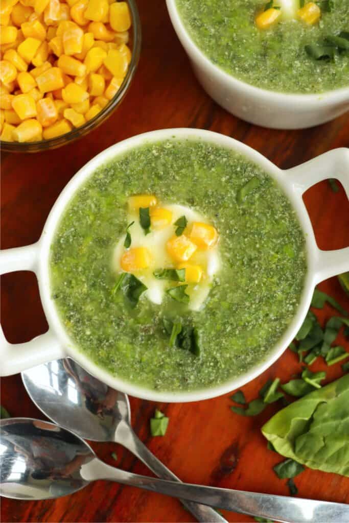 Overhead shot of kale and spinach soup topped with sour cream and corn. 